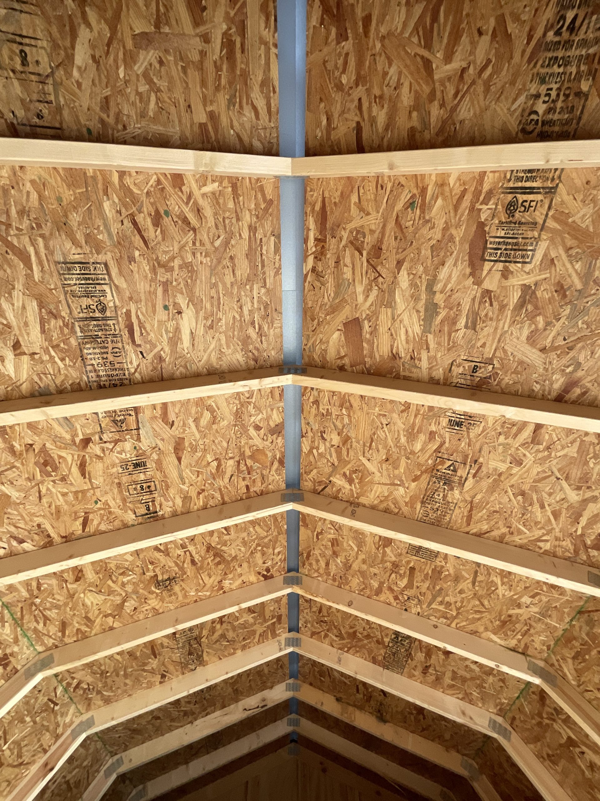 Interior roof structure with loft and rafters in barn style shed. Note the full-length ridge cap vent.