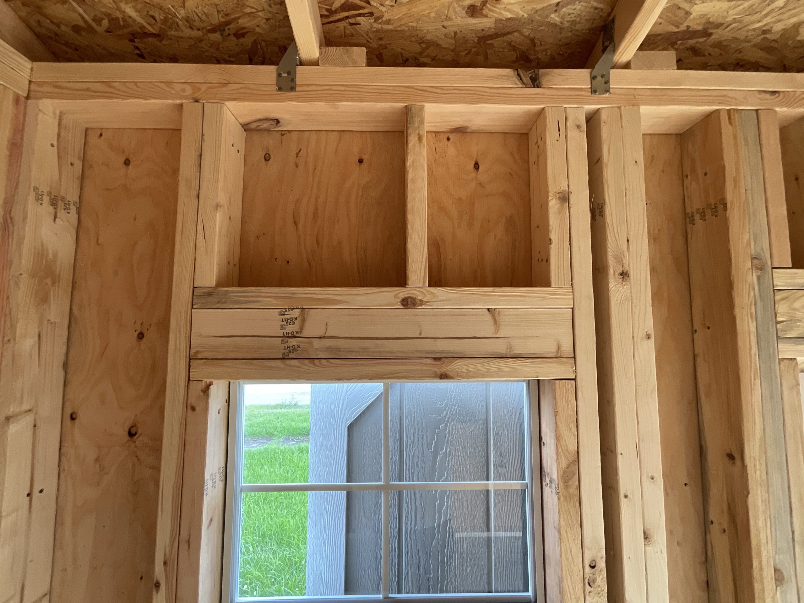 Interior wall framing showing house-style structural header above window in portable shed