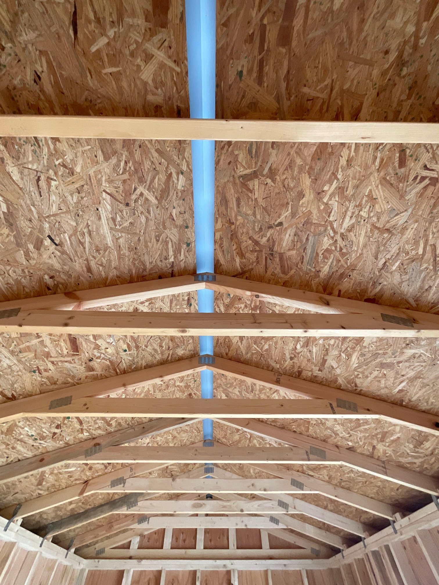 Engineered roof trusses with OSB roof decking and continuous ridge vent.