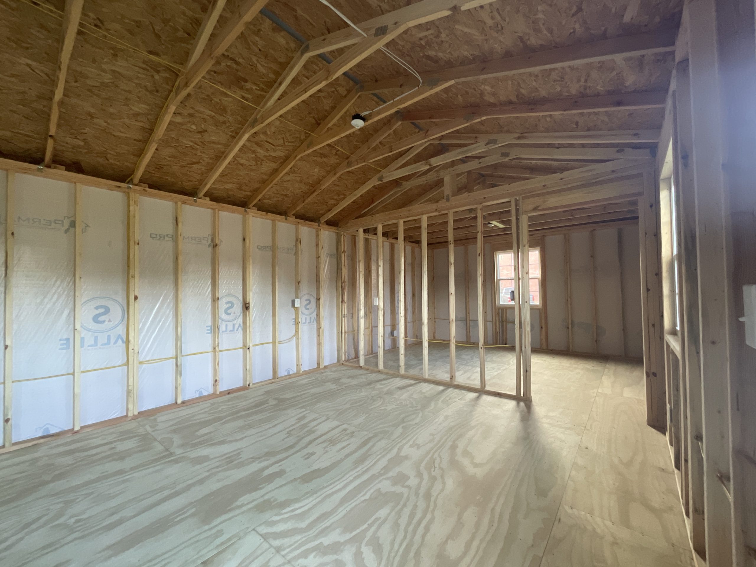 Open living room with framed bedroom in 14x44 House Shell