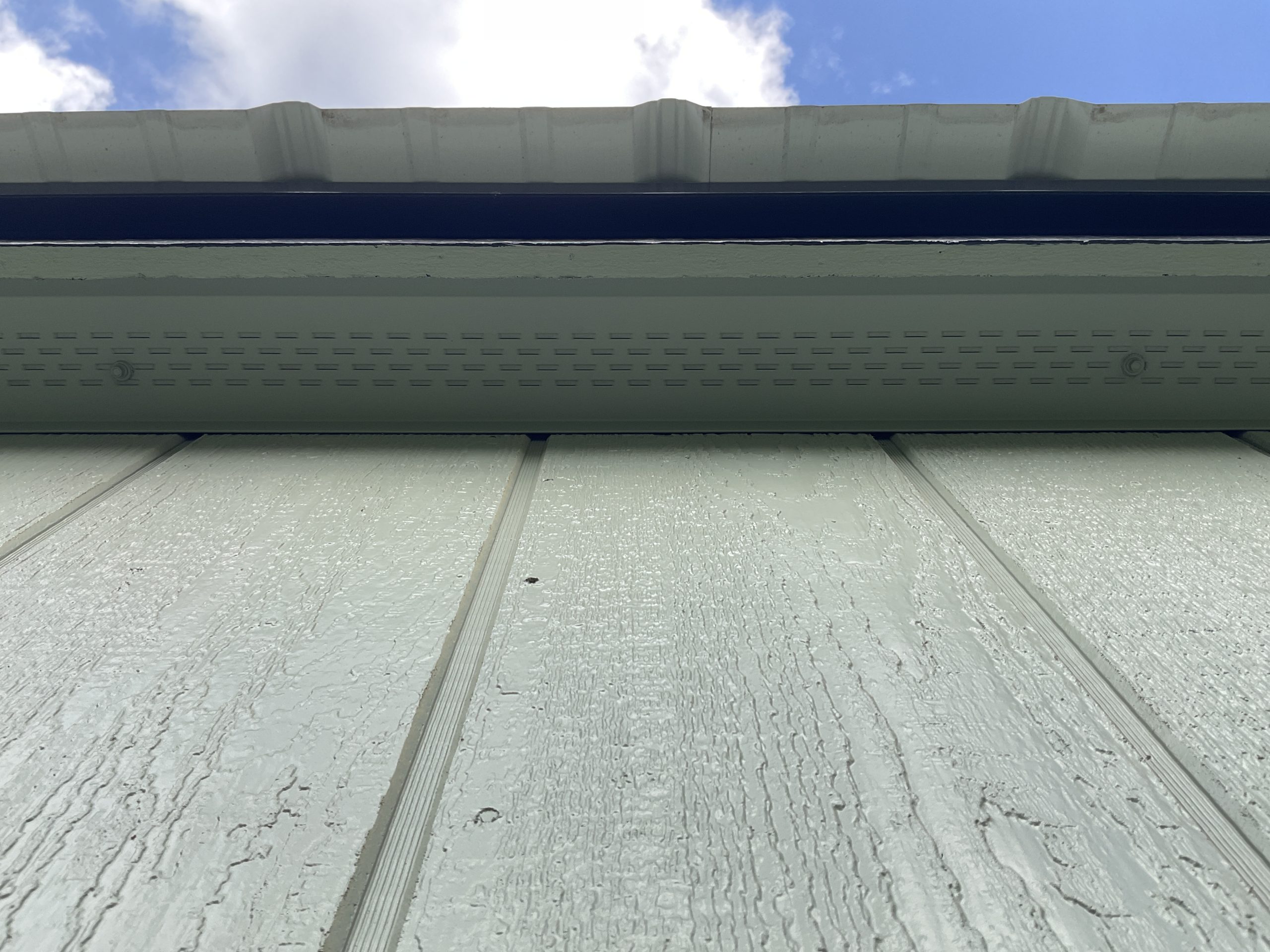 Continuous soffit vent under roof overhang
