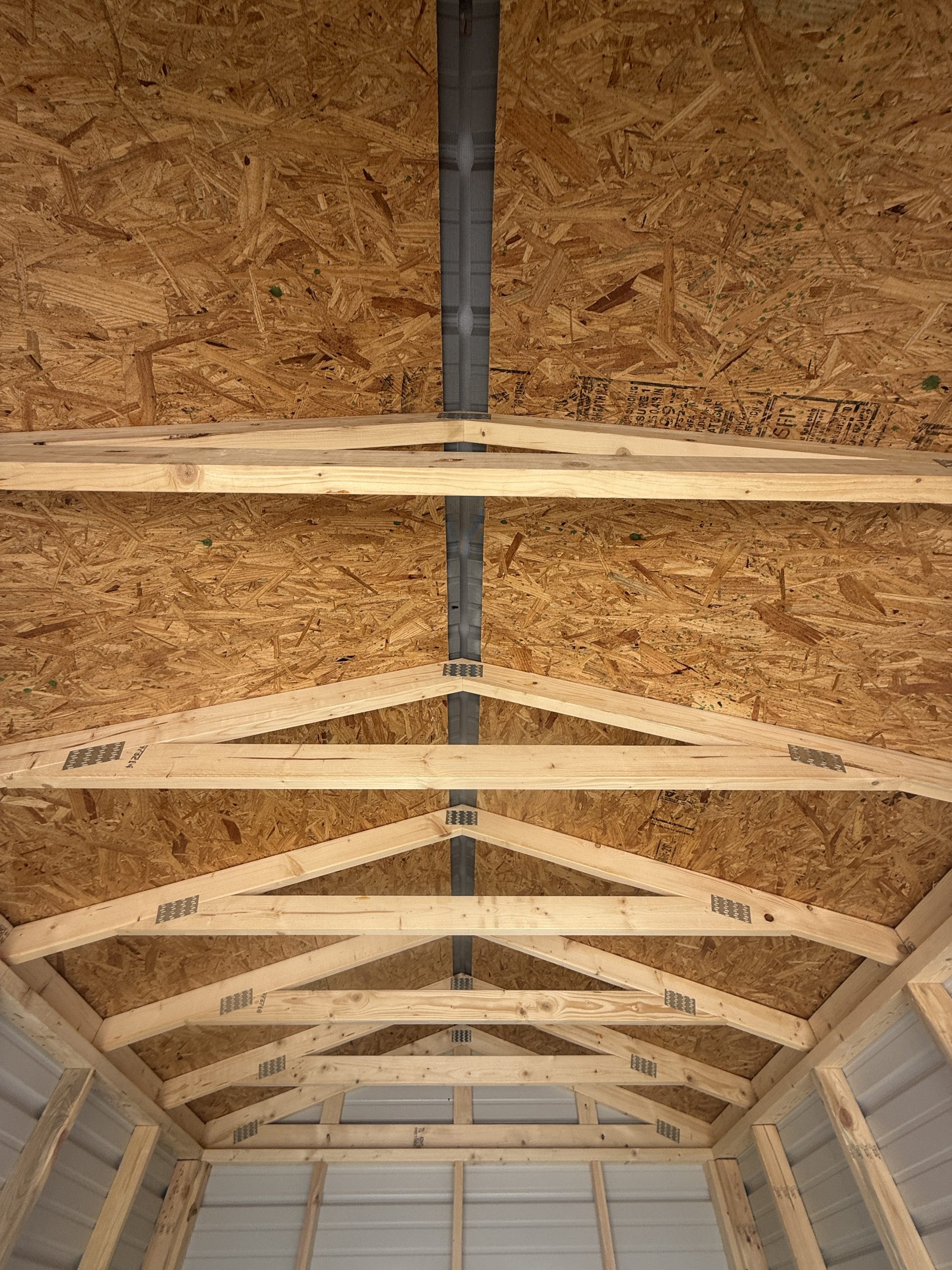 Interior roof view of 8x12 storage shed showing engineered trusses roof decking and full length ridge vent
